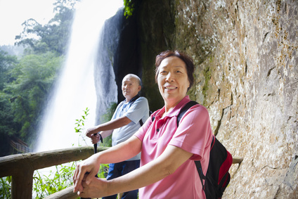 asian senior couple hiking in the mountain with waterfall
